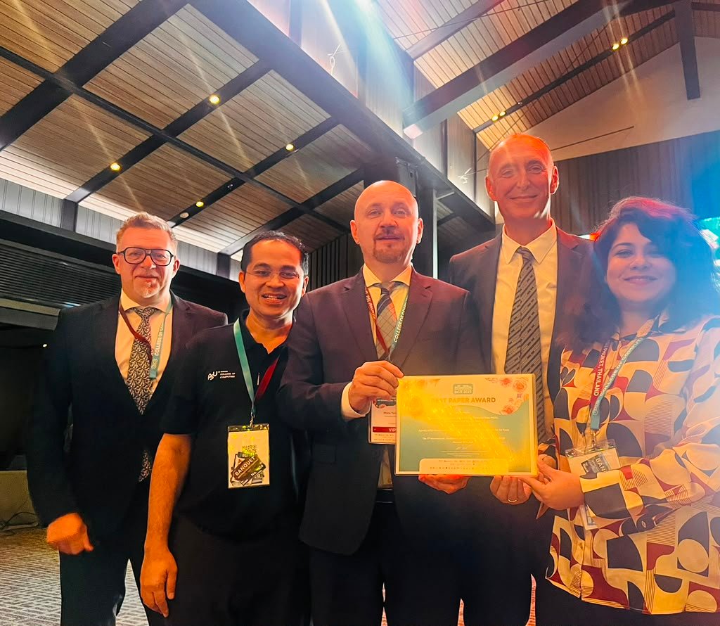 Swarnamouli Majumdar with conference organizers holding an IncIT Best Paper award.